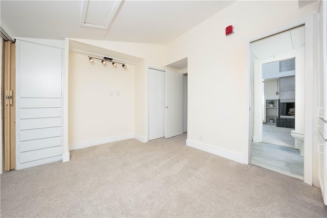 unfurnished bedroom featuring light carpet, connected bathroom, and vaulted ceiling