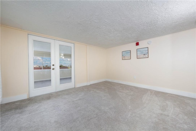 carpeted empty room with french doors and a textured ceiling