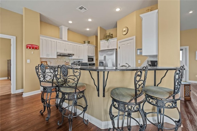 227 Windjammer St, Rockport, TX 78382 - kitchen featuring stainless steel appliances, under cabinet range hood, dark countertops, dark wood-style floors, and recessed lighting