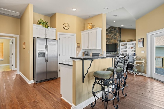 227 Windjammer St, Rockport, TX 78382 - kitchen featuring stainless steel fridge, dark countertops, white cabinetry, dark wood-style flooring, and vaulted ceiling
