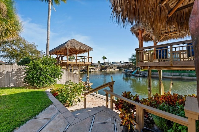 dock area with a gazebo, a deck with water view, a patio, and a lawn