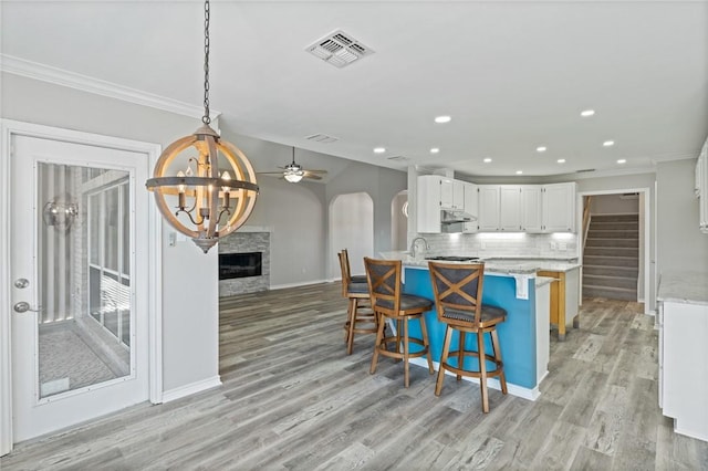 13845 Jolly Roger St, Corpus Christi, TX 78418 - kitchen with open floor plan, under cabinet range hood, ornamental molding, a chandelier, and white cabinets