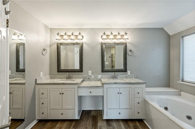 bathroom featuring a bathing tub, hardwood / wood-style floors, vanity, and vaulted ceiling