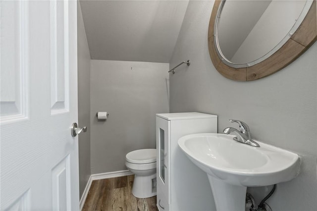 bathroom with toilet, wood-type flooring, sink, and vaulted ceiling