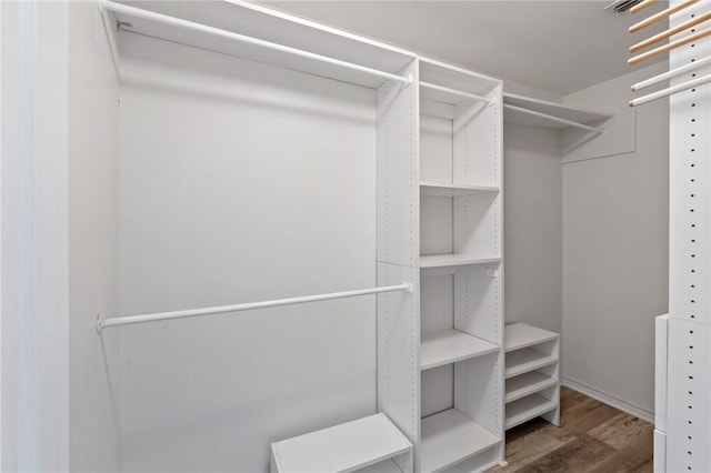 walk in closet with dark hardwood / wood-style floors