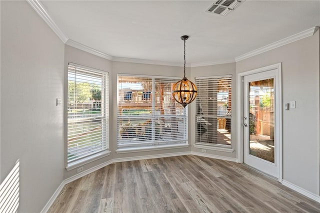 unfurnished dining area featuring crown molding, hardwood / wood-style floors, and a notable chandelier