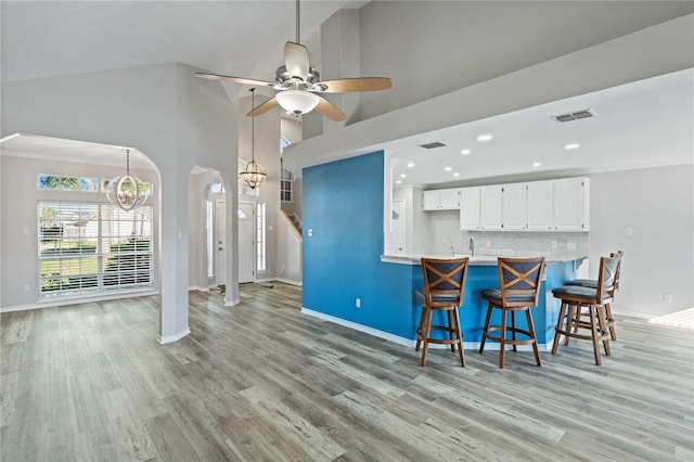 kitchen with a breakfast bar, white cabinets, tasteful backsplash, light hardwood / wood-style floors, and kitchen peninsula