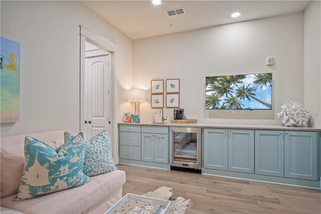 sitting room with wine cooler, light hardwood / wood-style floors, and indoor wet bar