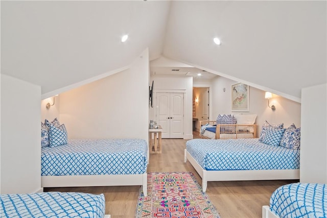 bedroom with lofted ceiling, crown molding, and light hardwood / wood-style flooring