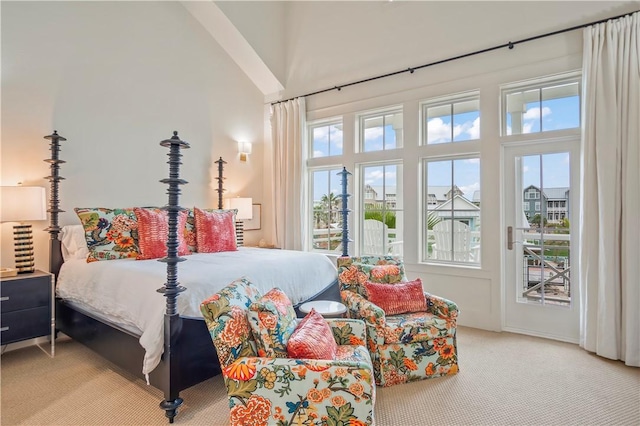 carpeted bedroom with access to exterior and a high ceiling