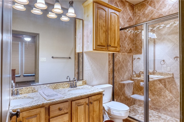 bathroom with a shower with shower door, vanity, and toilet