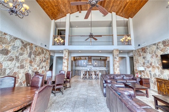 living room with beam ceiling, high vaulted ceiling, sink, decorative columns, and ceiling fan with notable chandelier