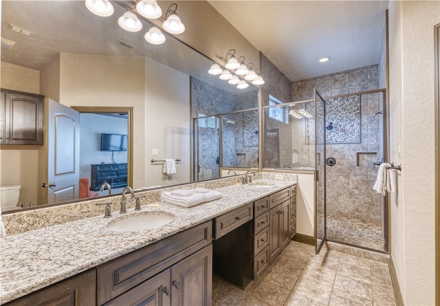 bathroom featuring a shower with door, vanity, a textured ceiling, tile patterned flooring, and toilet