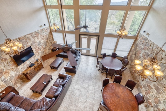 living room with a high ceiling, french doors, and ceiling fan with notable chandelier