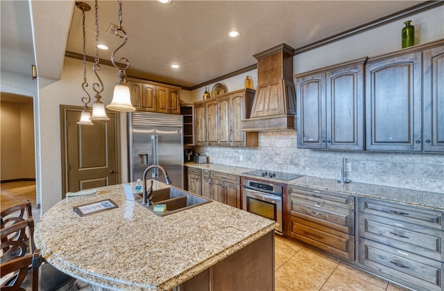 kitchen featuring stainless steel appliances, a center island with sink, sink, custom exhaust hood, and ornamental molding