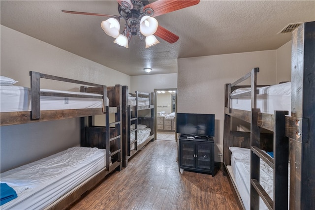 bedroom with dark wood-type flooring, ensuite bath, ceiling fan, and a textured ceiling