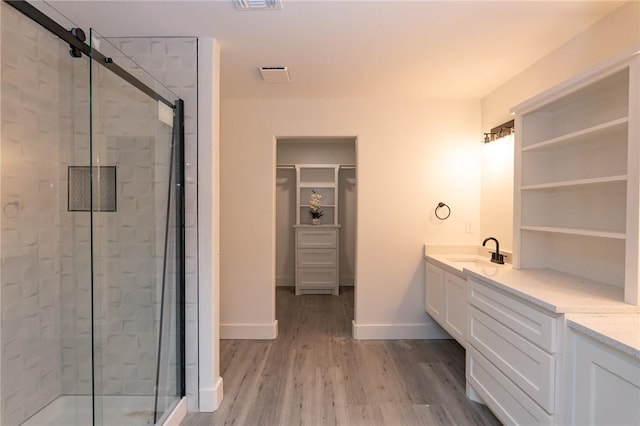 bathroom with wood-type flooring, vanity, and a shower with shower door