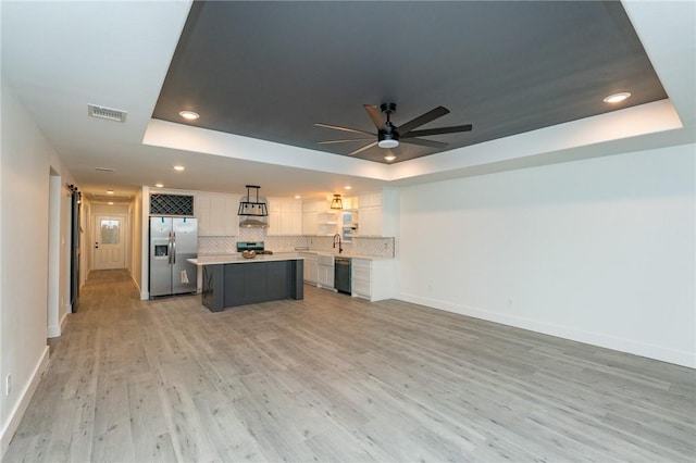 kitchen with appliances with stainless steel finishes, a center island, and a raised ceiling