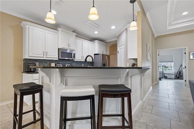 15229 Capstan St, Corpus Christi, TX 78418 - kitchen featuring appliances with stainless steel finishes, crown molding, backsplash, a breakfast bar area, and white cabinets