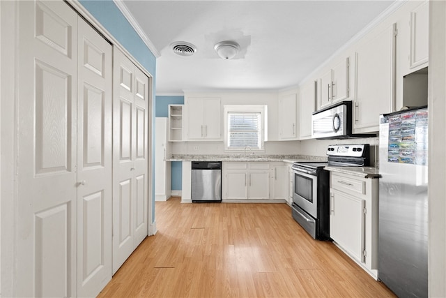 kitchen with white cabinets, crown molding, light hardwood / wood-style floors, and stainless steel appliances