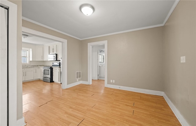 spare room with ornamental molding and light hardwood / wood-style flooring