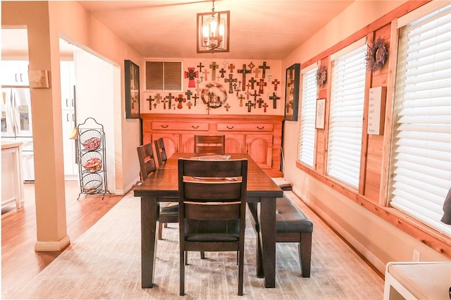 dining area featuring light wood-type flooring and a notable chandelier