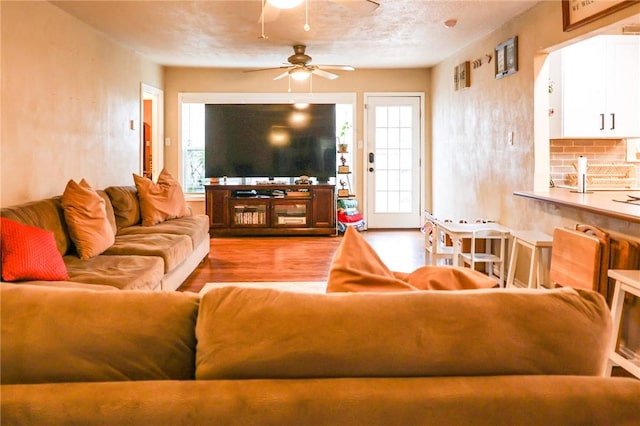 living room featuring ceiling fan, light hardwood / wood-style flooring, and a textured ceiling