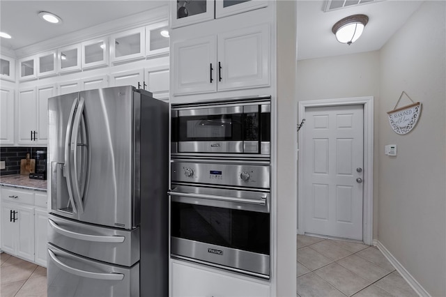 kitchen with tasteful backsplash, white cabinetry, light tile patterned flooring, and stainless steel appliances