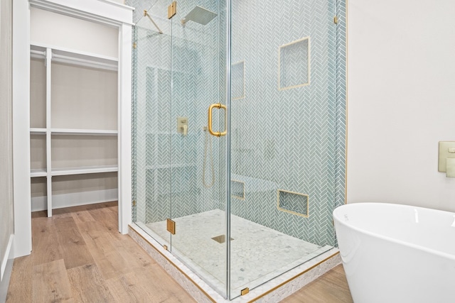 bathroom with wood-type flooring and shower with separate bathtub