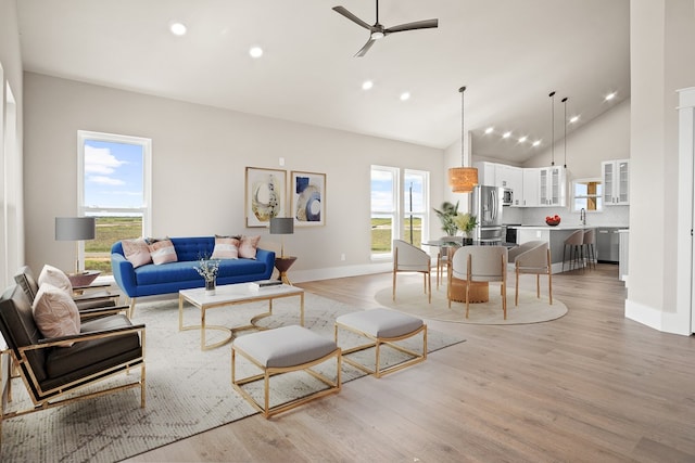 living room featuring light hardwood / wood-style floors, ceiling fan, sink, and high vaulted ceiling