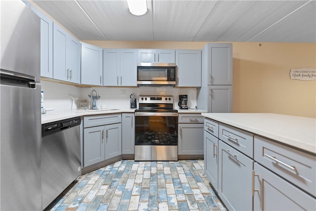 kitchen featuring sink, gray cabinetry, appliances with stainless steel finishes, and decorative backsplash