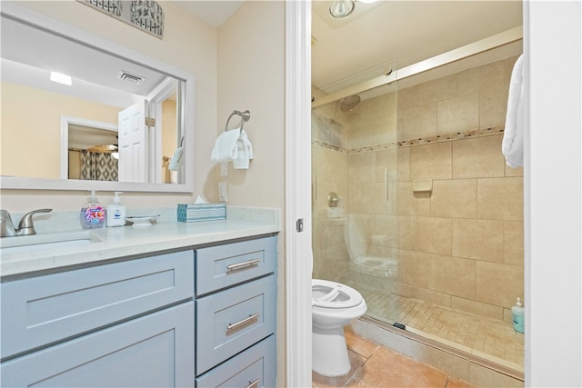 bathroom with tiled shower, vanity, tile patterned floors, and toilet