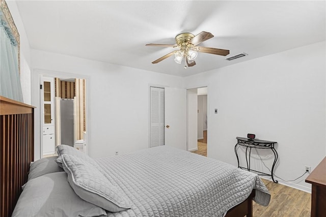 bedroom with connected bathroom, light hardwood / wood-style floors, a closet, and ceiling fan