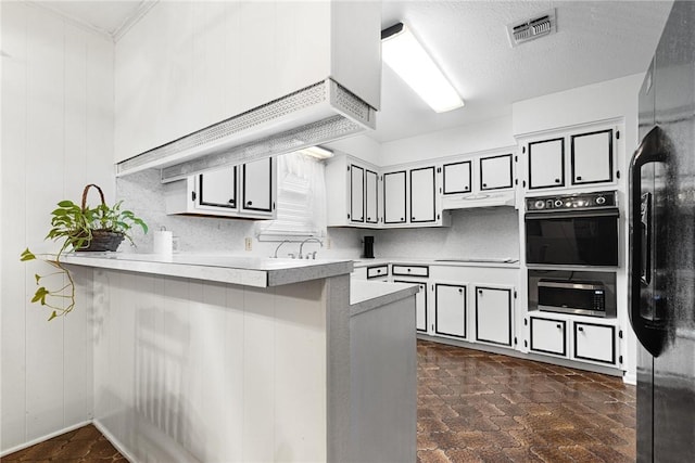 kitchen with sink, black appliances, a textured ceiling, a kitchen bar, and kitchen peninsula