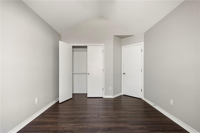 unfurnished bedroom featuring dark wood-style floors, lofted ceiling, a closet, and baseboards