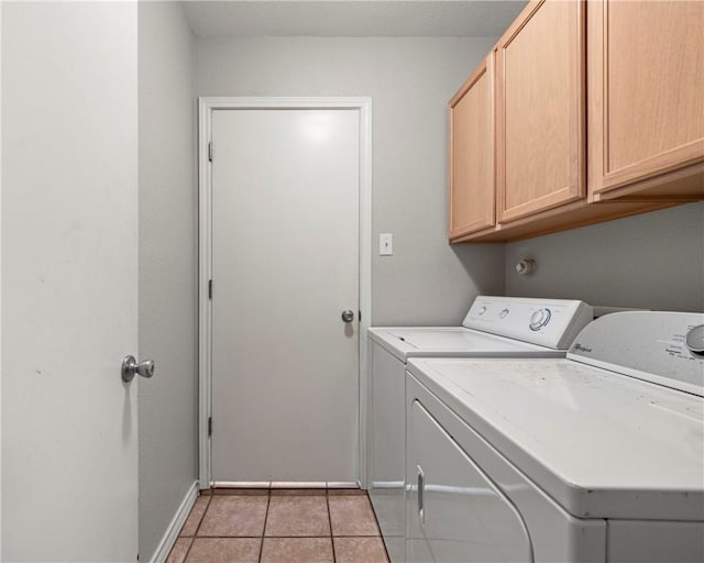 clothes washing area featuring cabinet space, light tile patterned floors, baseboards, and separate washer and dryer