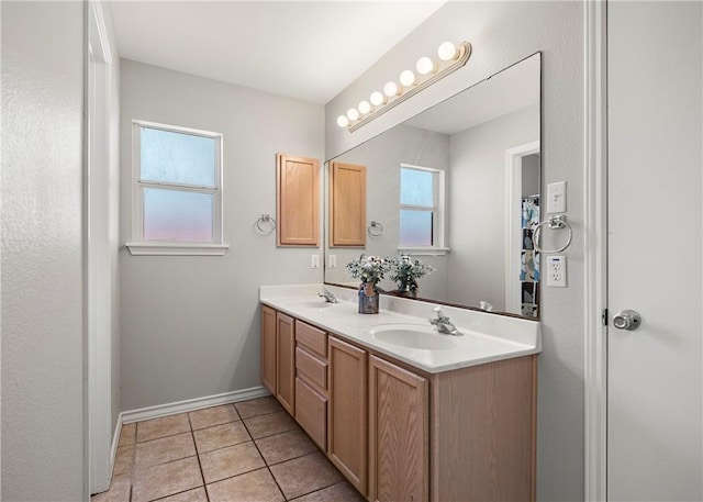 bathroom featuring double vanity, baseboards, a sink, and tile patterned floors