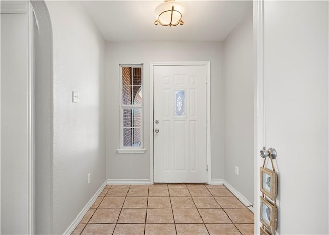 foyer entrance with arched walkways, light tile patterned flooring, and baseboards