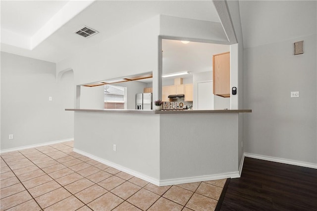 kitchen with baseboards, under cabinet range hood, visible vents, and stainless steel fridge with ice dispenser