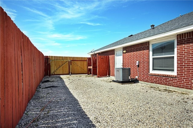 view of yard with central air condition unit, a gate, and fence