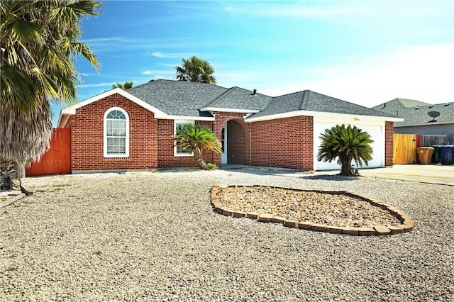 single story home featuring roof with shingles, brick siding, an attached garage, fence, and driveway