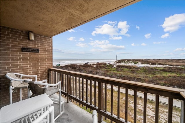 balcony featuring a view of the beach and a water view