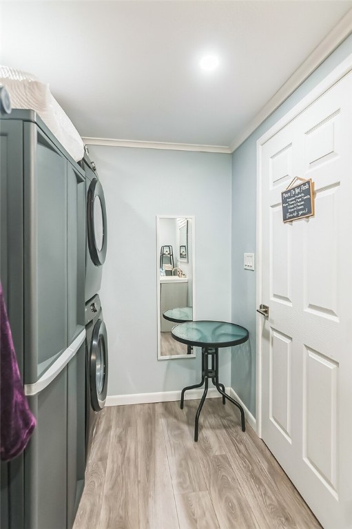 14300 S Padre Island Dr Unit 163, Corpus Christi, TX 78418 - laundry area with stacked washer and clothes dryer, crown molding, light wood-type flooring, and baseboards