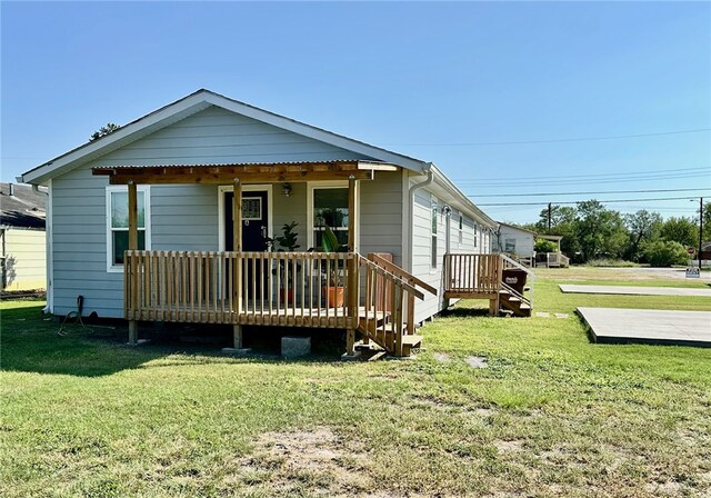 back of property featuring a wooden deck and a lawn