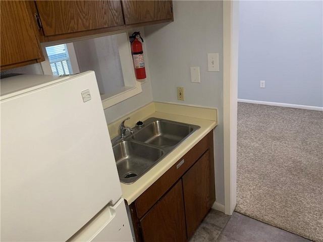 kitchen with white fridge, sink, and light carpet