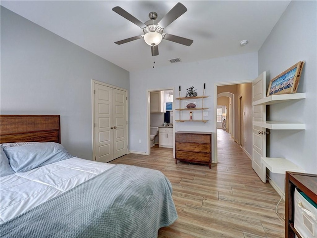 bedroom featuring light wood-style flooring, arched walkways, a ceiling fan, and baseboards