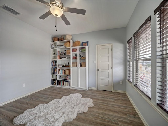 living area featuring wood finished floors, a ceiling fan, and baseboards