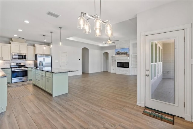 15101 Tesoro Dr, Corpus Christi, TX 78418 - kitchen featuring appliances with stainless steel finishes, ceiling fan, arched walkways, light wood-style flooring, and a center island