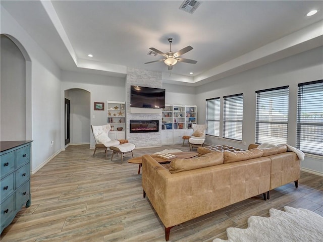 living area featuring arched walkways, a ceiling fan, light wood-style flooring, healthy amount of natural light, and recessed lighting