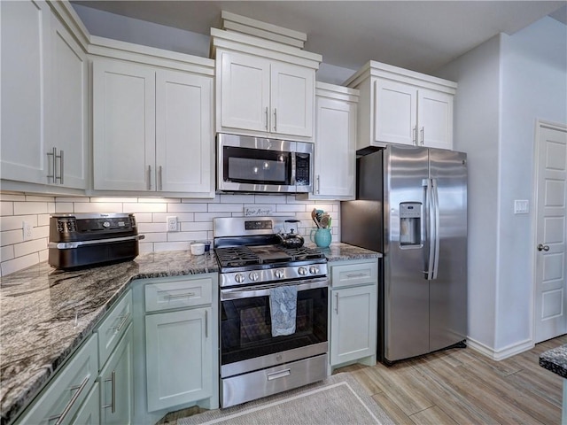 kitchen featuring appliances with stainless steel finishes, light wood-style floors, tasteful backsplash, and stone counters